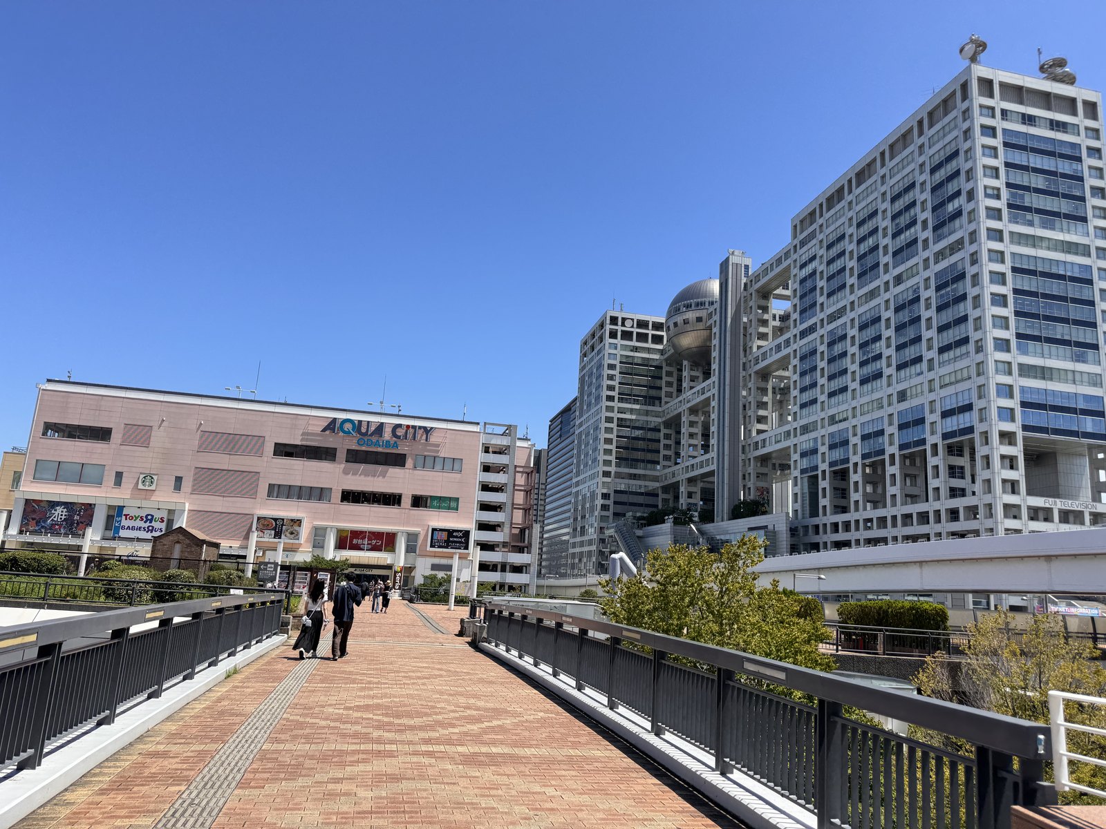 A wide elevated walkway in Odaiba with no shade, under a bright summer sky