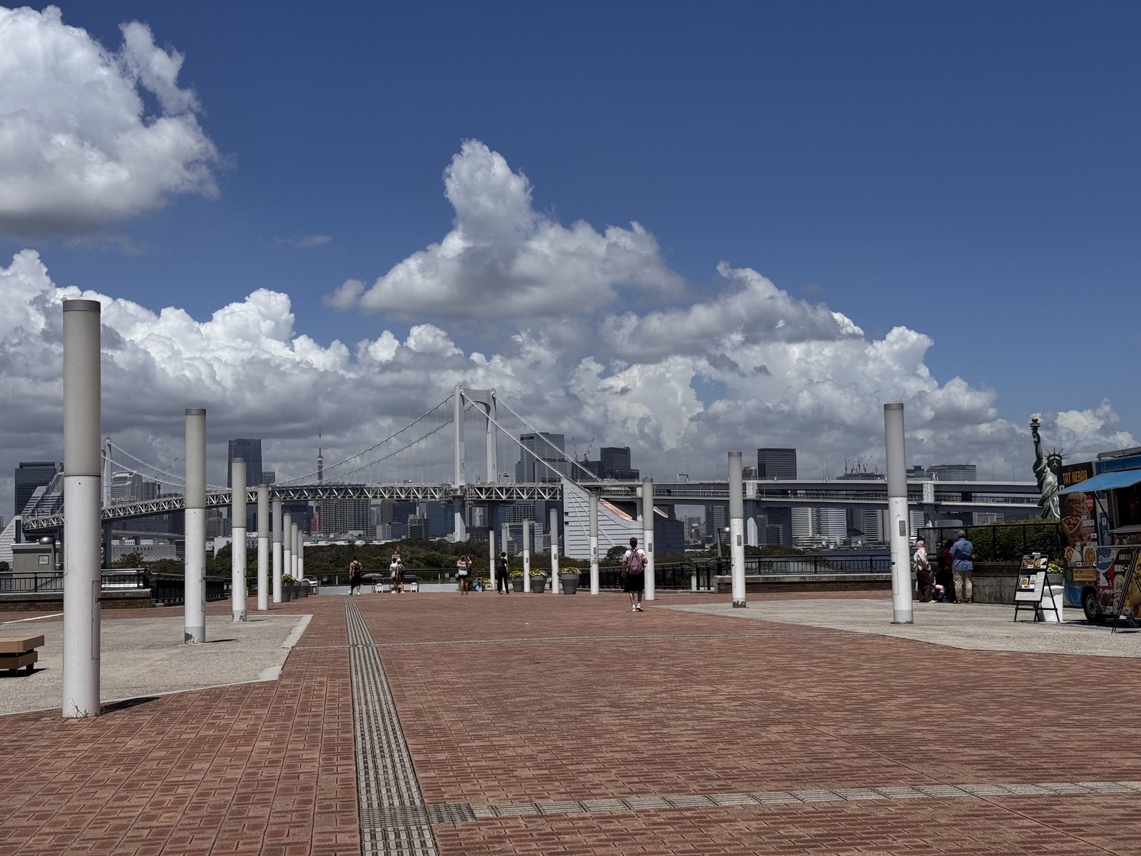 An open paved plaza in Odaiba with Rainbow Bridge in the background