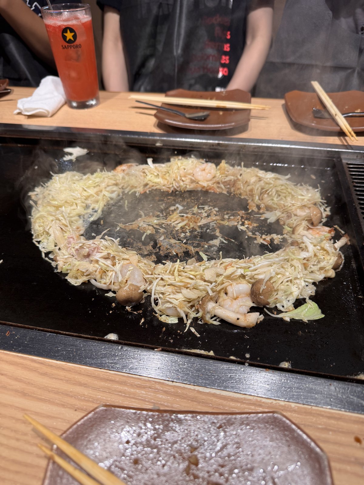 A ring of cabbage built on the griddle with a well in the middle for the batter