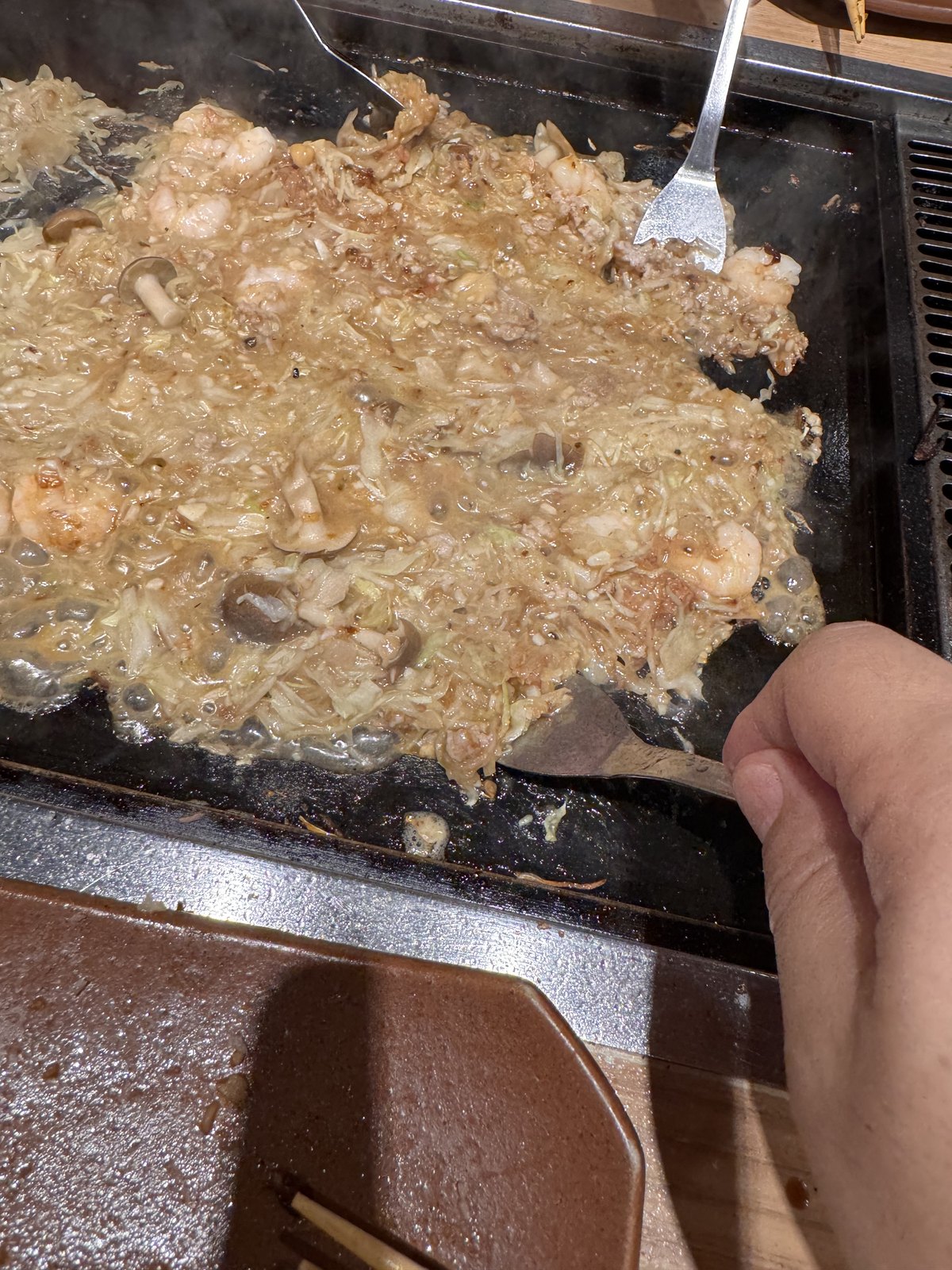 Finished monjayaki spread across the hotplate, ready to eat with a small spatula